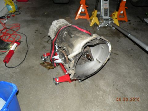 2000 Porsche Carrera - Transmission unit on a stand in a garage setting, with shop equipment visible.