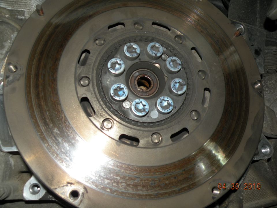 Clutch pressure plate and flywheel with visible wear marks and eight Torx bolts