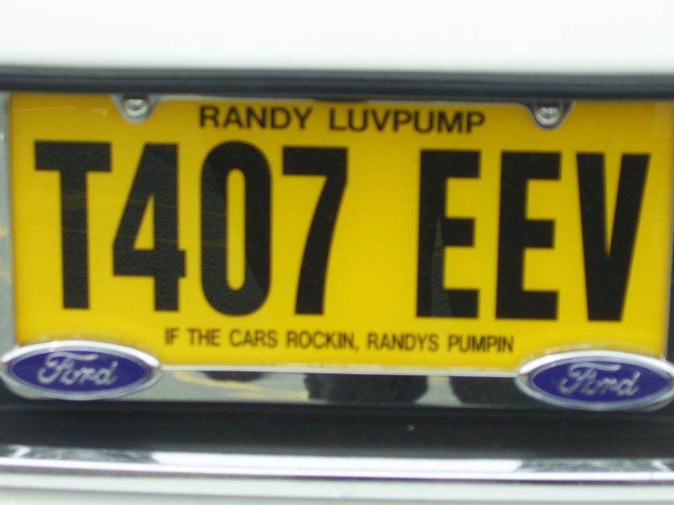 Yellow plate T407 EEV in chrome Ford frame with 'Randy Luvpump' novelty text on white car