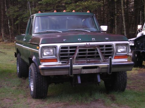 1978 Ford Bronco - This green Ford truck, possibly from 1978, features a prominent push bar and roof-mounted lights.
