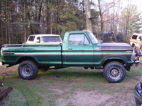 1978 Ford Bronco - A green Ford F-Series pickup truck is parked outdoors with a white camper shell loaded in its bed.