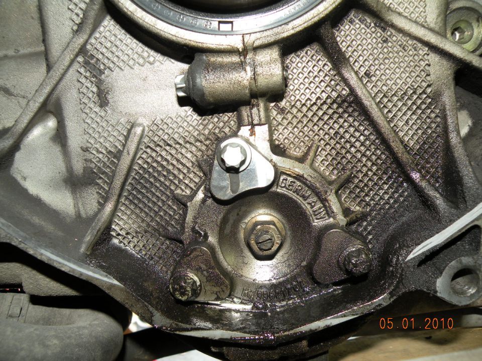 Engine casing with GERMANY stamped on it, showing oil residue and bolts