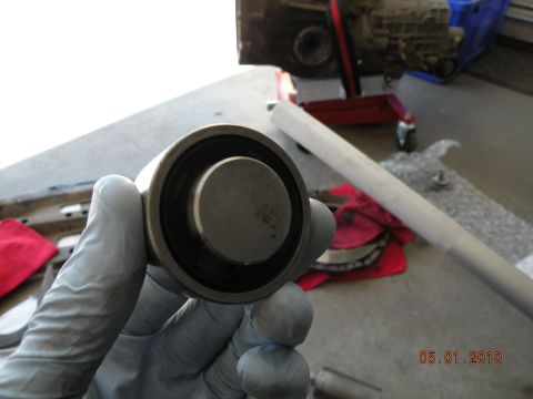2000 Porsche Carrera - A bearing is held in a gloved hand, with engine components visible in the background.