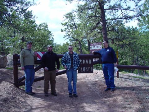 1993 Ford Bronco - A group of men are stopped at a closed road, indicated by a wooden gate and sign.