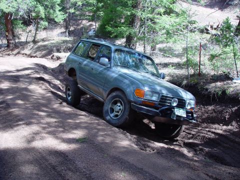 1993 Ford Bronco - Toyota Land Cruiser FJ80 navigating an off-road trail with steep inclines.