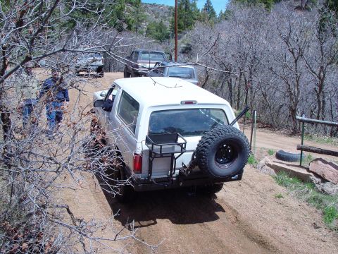 1993 Ford Bronco - A white SUV navigates a dirt path, with other vehicles visible in the background.