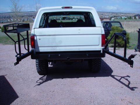 1993 Ford Bronco - Rear view of a white 1993 Ford Bronco equipped with a swing-away tire carrier and a side-mounted cargo rack.