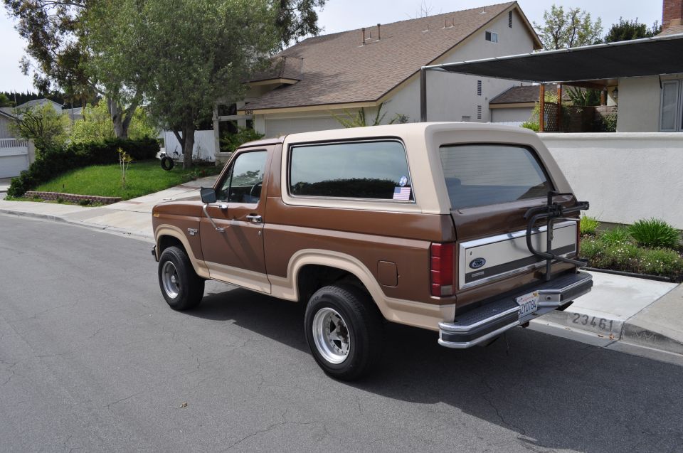 Brown 1986 Ford Bronco parked on a residential street, rear 3/4 view
