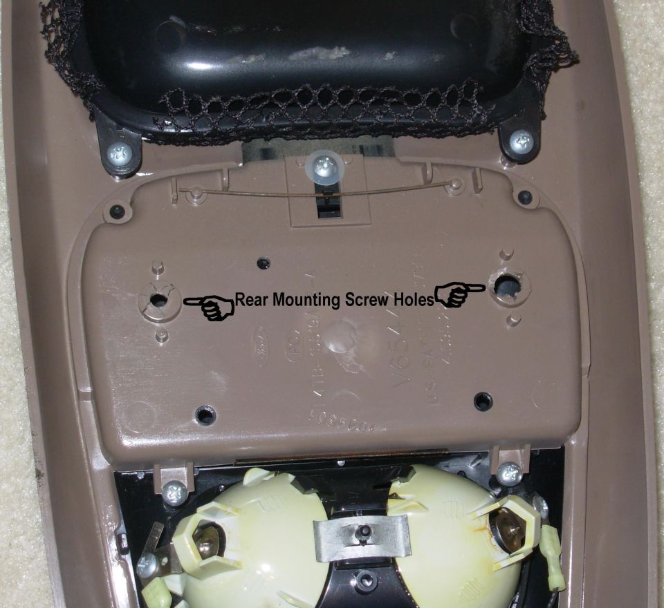 Underside of a tan center console showing mounting holes