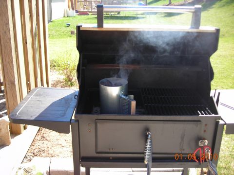 1984 Ford Bronco - A charcoal chimney starter is smoking inside a black grill on a sunny day.