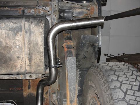1995 Ford Bronco - A new exhaust pipe is being installed on a vehicle, showing the undercarriage and suspension components.