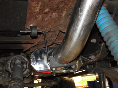 1995 Ford Bronco - The underside of a vehicle shows a polished exhaust pipe system attached to a heavily rusted frame.
