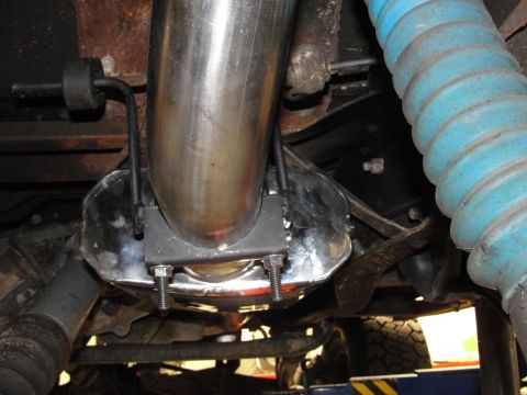 1995 Ford Bronco - Close-up view of an exhaust pipe clamp and shield, showing mechanical components underneath a vehicle.