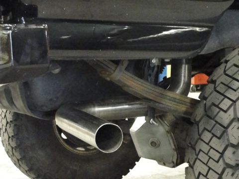 1995 Ford Bronco - Close-up view of the exhaust system and rear suspension components of a vehicle.