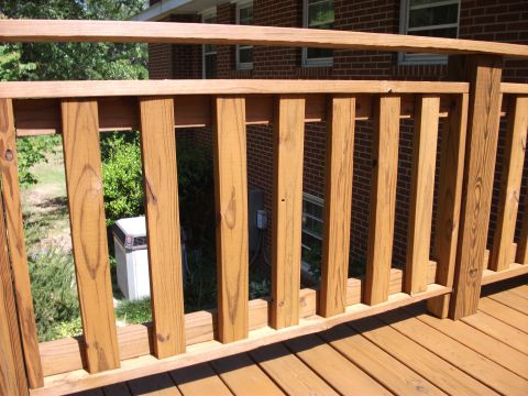 1992 Ford F-150 - Freshly stained wooden deck railing with vertical balusters alongside a brick house, with an outdoor AC condenser unit and shrubs visible t…