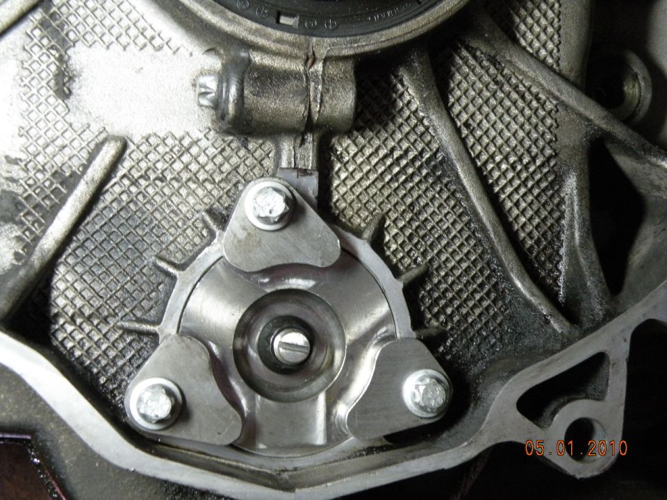 Close-up of engine component with three bolts securing a metal plate
