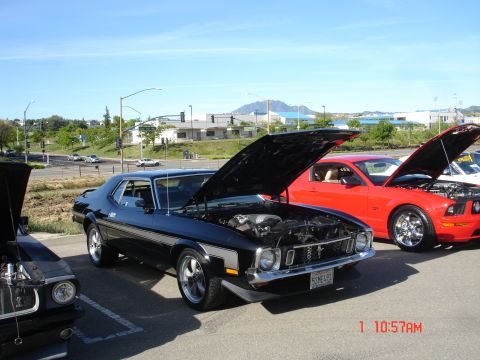 1978 Ford Mustang II - Two Ford Mustangs, one classic and one modern, parked side-by-side with hoods open on a sunny day.
