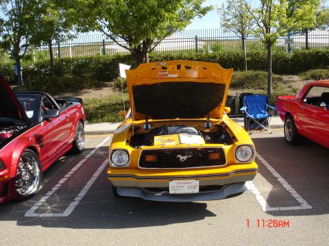 1978 Ford Mustang II - A yellow 1978 Ford Mustang II is parked next to a red convertible, both with hoods open.