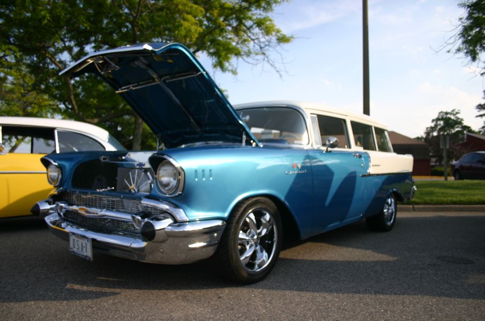 Blue and white 1957 Chevrolet station wagon, hood open, parked next to yellow car