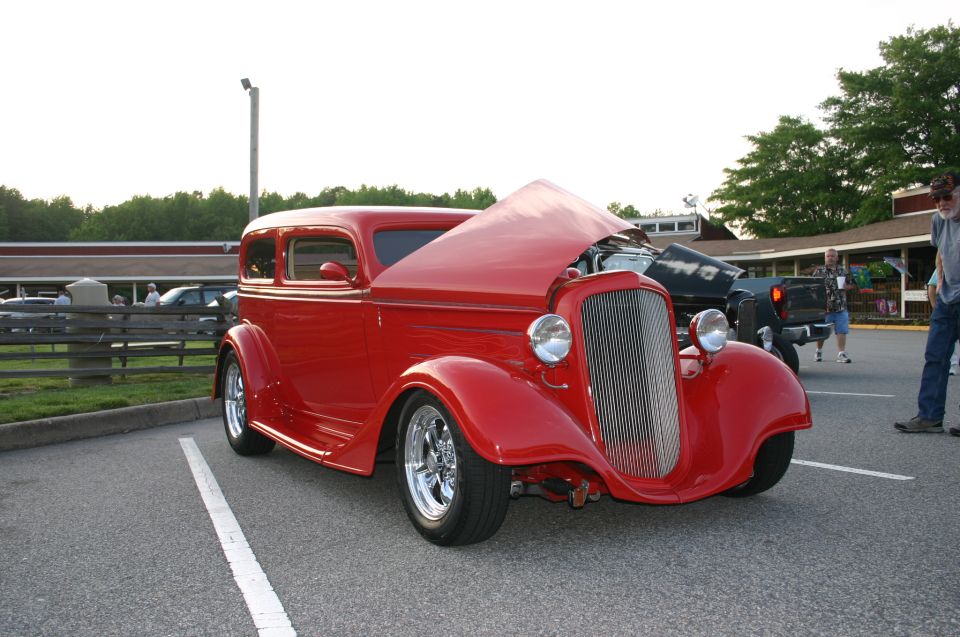 Red hot rod sedan, hood open, front view. Custom grille and headlights