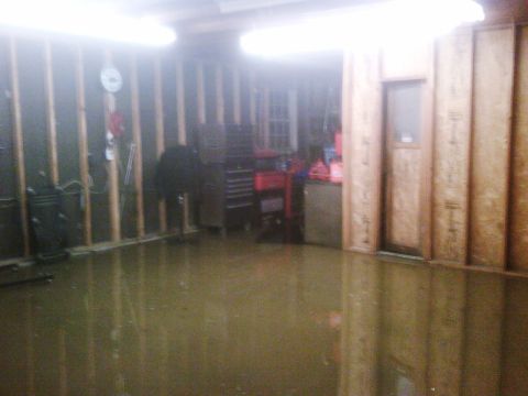 2007 Ford Mustang - The garage floor is covered in water, reflecting the overhead lights and the unfinished walls.
