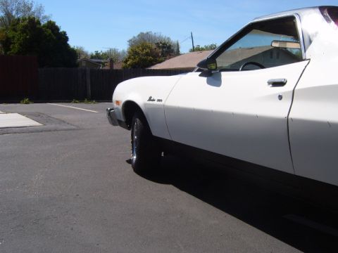 1973 Ford Ranchero - A white 1973 Ford Ranchero is parked in a lot under a clear blue sky.