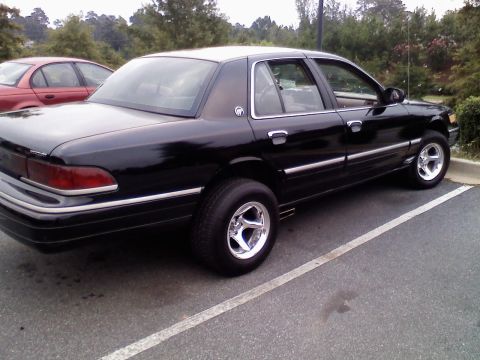 1993 Mercury Grand Marquis - A black 1993 Mercury Grand Marquis is parked next to a red sedan.