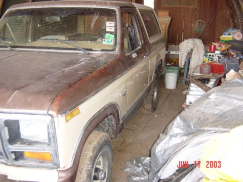 1984 Ford Bronco - This two-tone SUV, likely from the early 1980s, is seen parked indoors amidst clutter.
