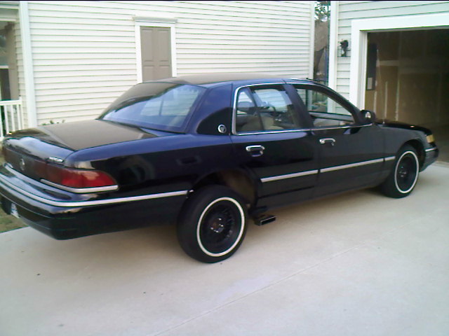 Black 1990s Mercury Grand Marquis sedan on driveway with black steel wheels