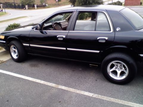 1993 Mercury Grand Marquis - This black sedan is parked in a lot, showing its side profile and chrome accents.