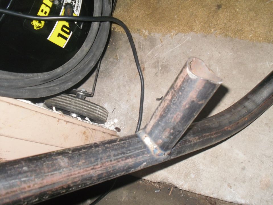 Close-up of welded metal tubing with a black cable and a yellow and black object with the number 10 on it in the background