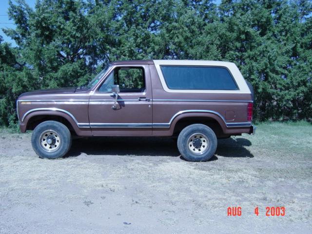 Brown Ford Bronco with a white top, parked outside