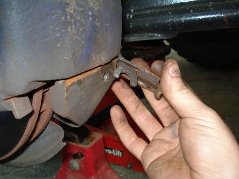 1984 Ford Bronco - Close-up of a hand holding a brake caliper bracket clip during a brake job.