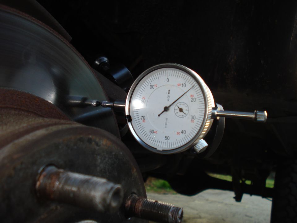 Dial indicator measuring brake rotor runout on a rusty hub assembly