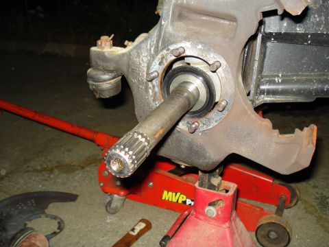 1984 Ford Bronco - Vehicle brake assembly part shown on a jack stand, with a splined axle shaft visible.