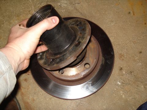 1984 Ford Bronco - Brake rotor and hub assembly being held by a hand.