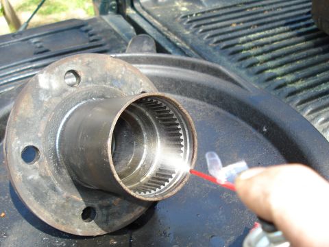 1984 Ford Bronco - A wheel hub assembly is being sprayed with lubricant, likely for maintenance or repair.