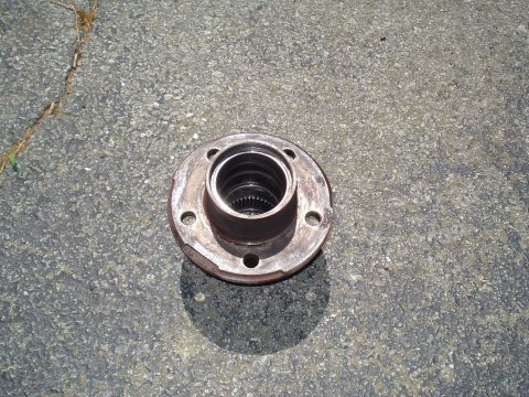 1984 Ford Bronco - A single wheel hub is shown on a paved surface, with a shadow cast by the sun.