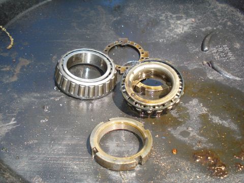 1984 Ford Bronco - Disassembled wheel bearings and a nut are shown in a pan with oil.