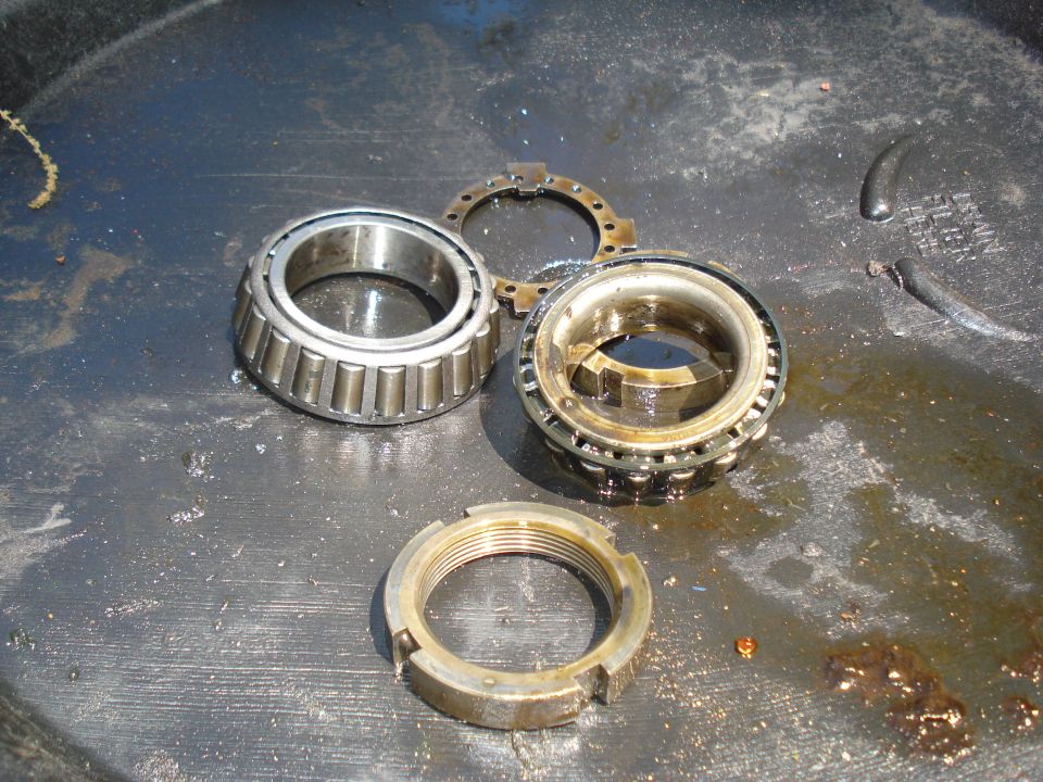 Wheel bearings and a threaded nut sitting in a greasy pan