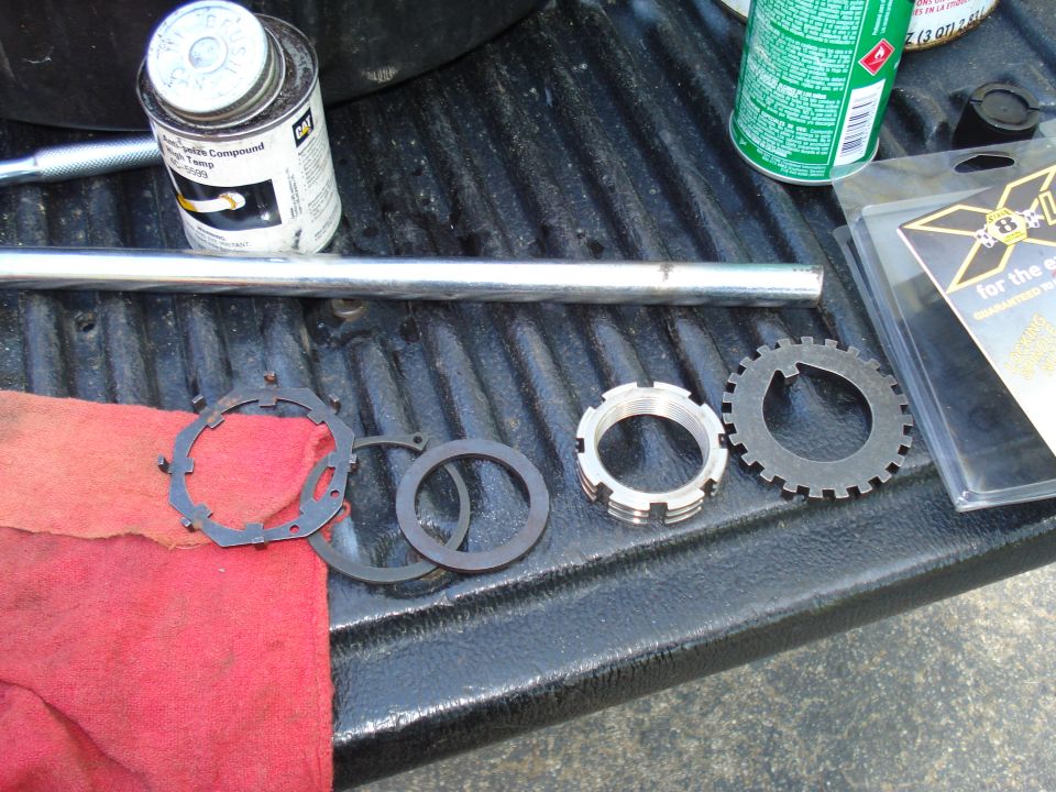 Metal brake parts, a red cloth, a tube of sealant, and a can of spray on a truck bed