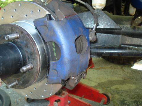 1984 Ford Bronco - A vehicle's brake system, a blue caliper and a drilled rotor, is shown in detail.