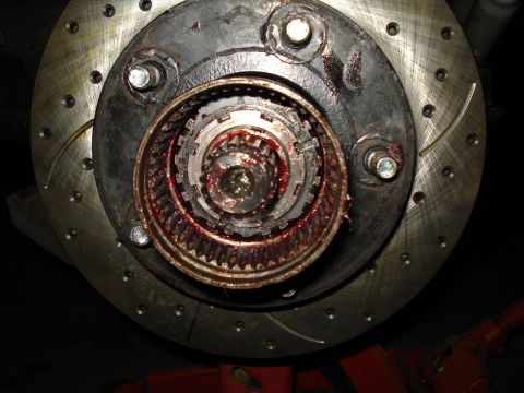 1984 Ford Bronco - Close-up of a front hub with the locking hub assembly removed, exposing the red-grease-packed splined axle shaft, internal clutch ring and…