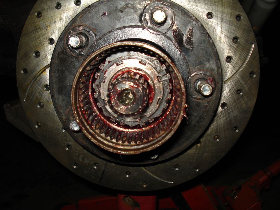 Exposed splined front axle hub packed with red grease inside a drilled and slotted brake rotor