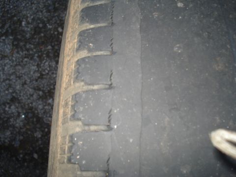 1994 Ford F-350 - Close-up of a heavily worn tire, showing damage to the tread blocks and sidewall.