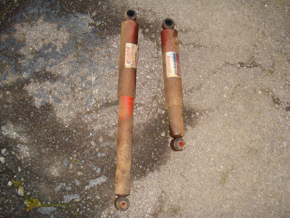 Two Gabriel shock absorbers with red bands on a concrete surface