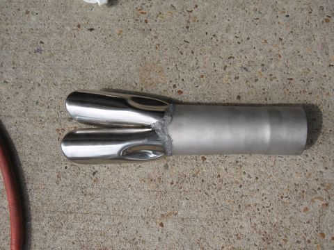 1968 Shelby GT500 - A pair of chrome exhaust tips are joined to a single pipe, with visible welds, lying on a concrete surface.