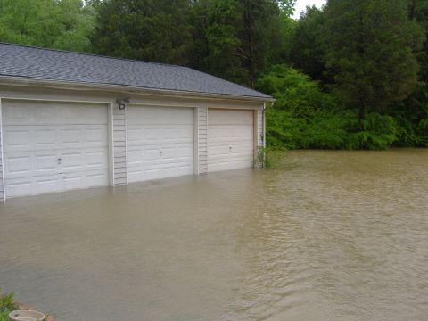 2007 Ford Mustang - A garage is submerged in floodwaters, with the water level reaching the bottom of the garage doors.