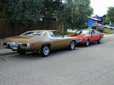 1979 Ford Bronco - A gold 1974 Plymouth Road Runner is parked on the street, with a red 1974 Dodge Charger behind it.