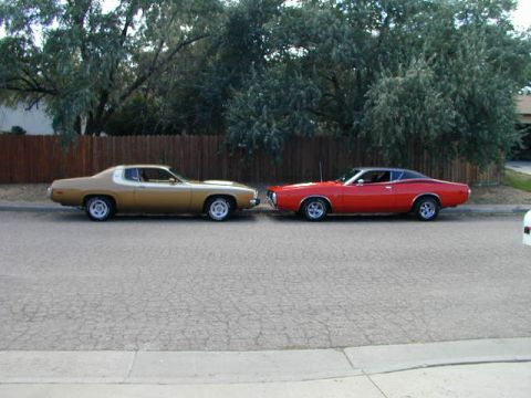 1979 Ford Bronco - Two vintage cars, a gold coupe and a red fastback, are parked parallel on a residential street.